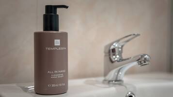 ”TEMPLESPA”-merkkinen käsisaippuan pullo on sijoitettu kylpyhuoneen pesualtaan viereen, ja altaassa on moderni hana.