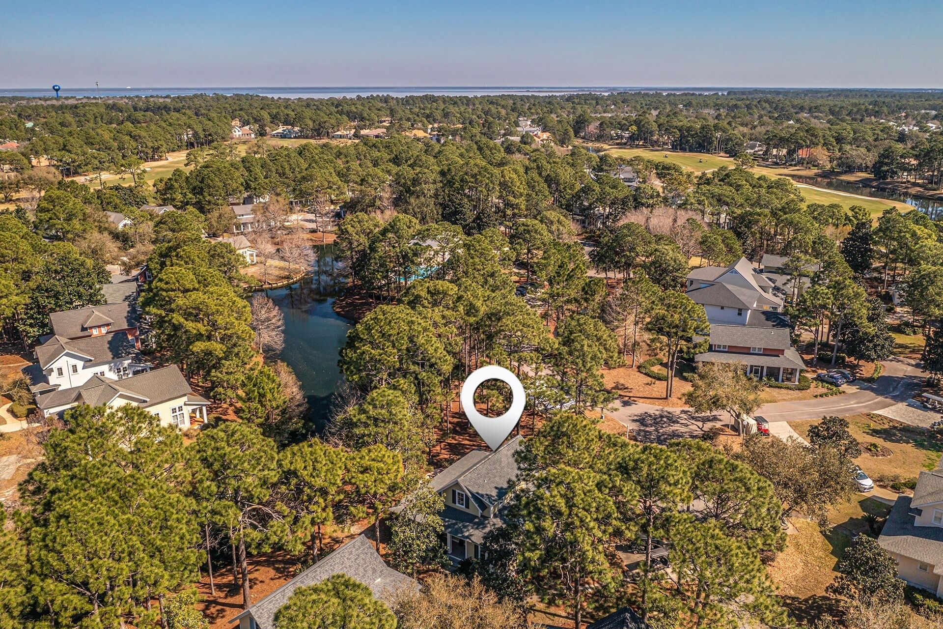 An aerial view of a residential area with houses, a lake, and a golf course.
