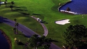 Un parcours de golf avec un plan d’eau et un club-house.