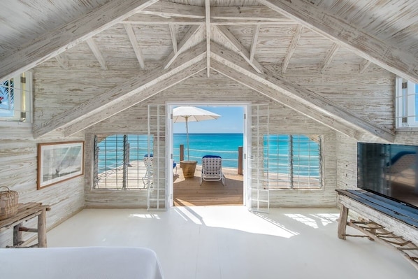 A room with a wooden ceiling, a large window, a TV, and a view of the beach. - Sunset Reach by Blue Sky Luxury (Mullins)