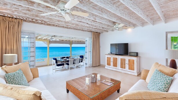 A spacious living room with a view of the sea, furnished with white sofas and a wooden coffee table. - Easy Reach by Blue Sky Luxury (Mullins)