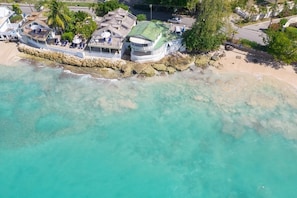 A coastal property with a large house, a boat dock, and a beach.