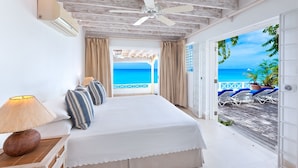 A bedroom with a bed, a nightstand, a lamp, and a view of the beach. - Easy Reach by Blue Sky Luxury (Mullins)