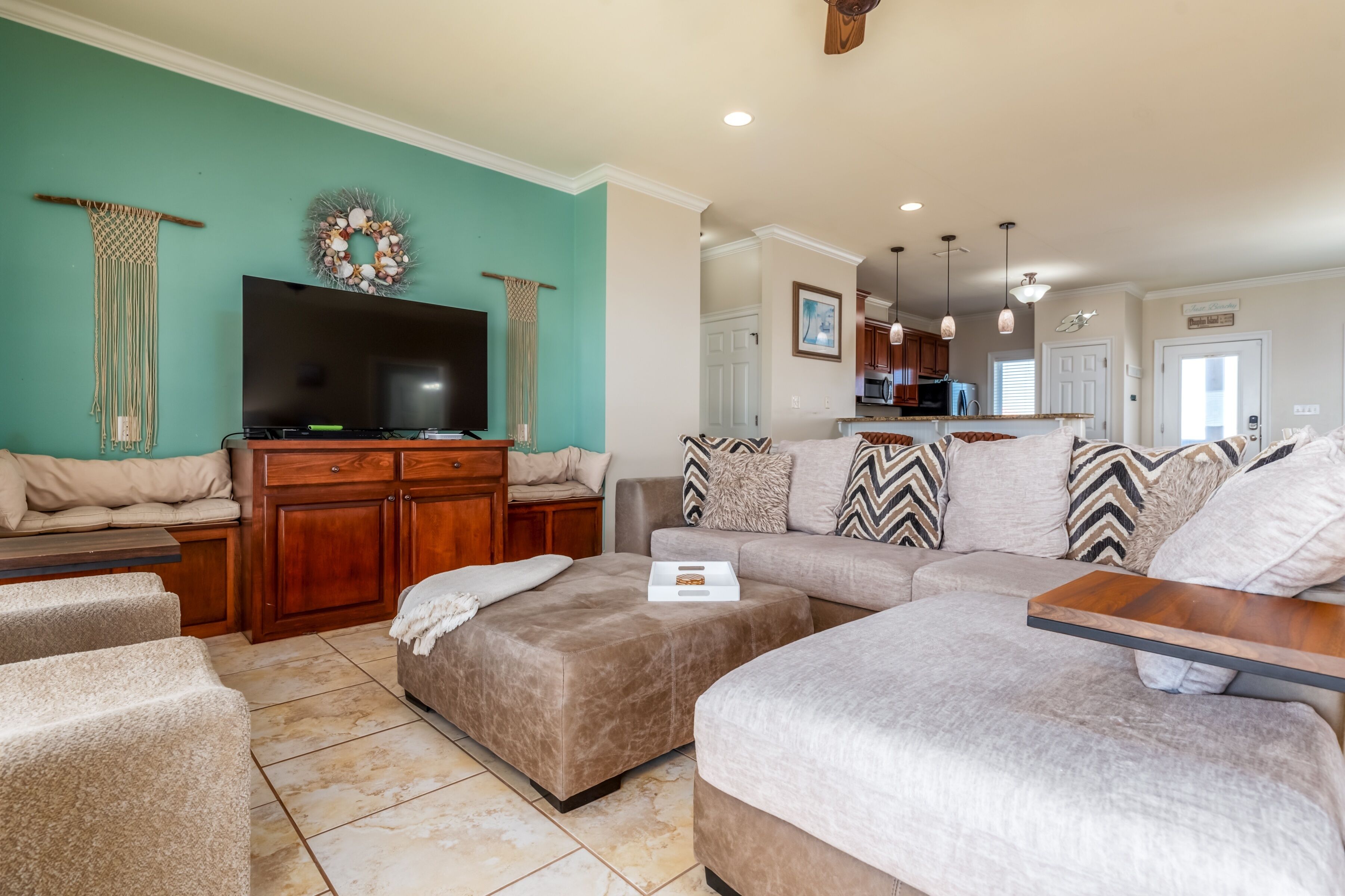 A spacious living room with a large sectional sofa, ottomans, and a flat-screen TV.