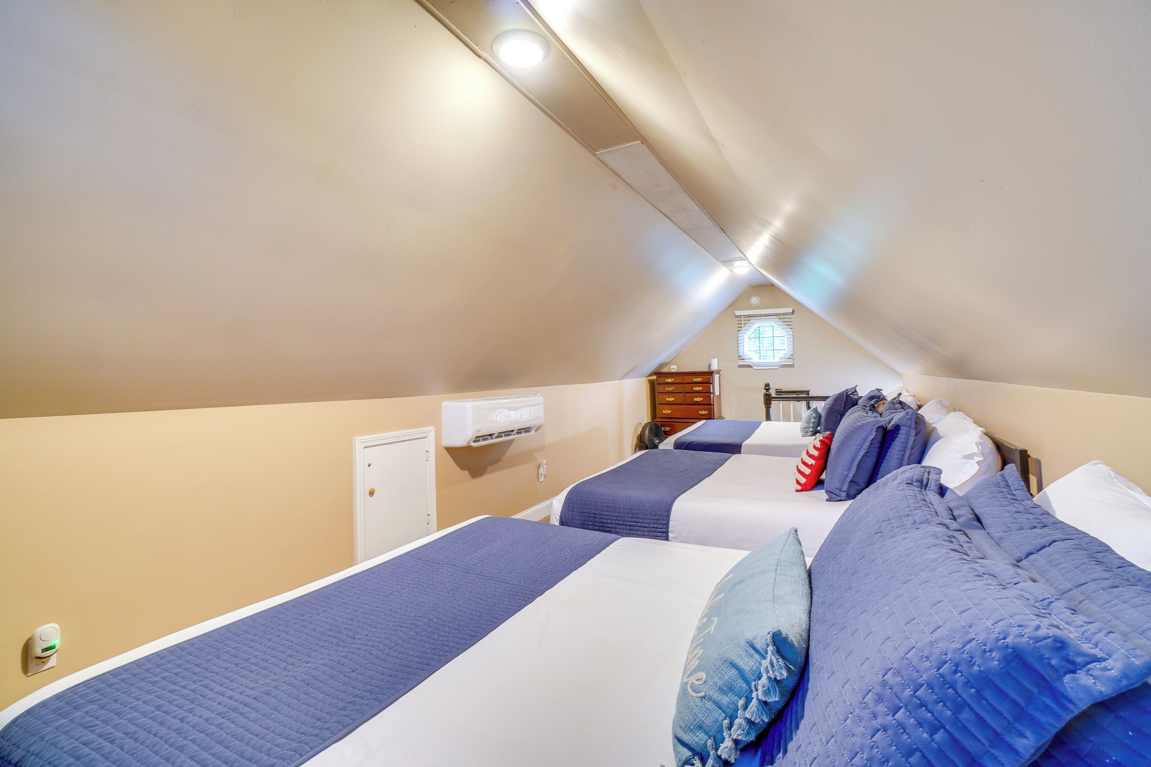 Une chambre d’hôtel avec deux lits, une fenêtre et une bouche d’aération au plafond.