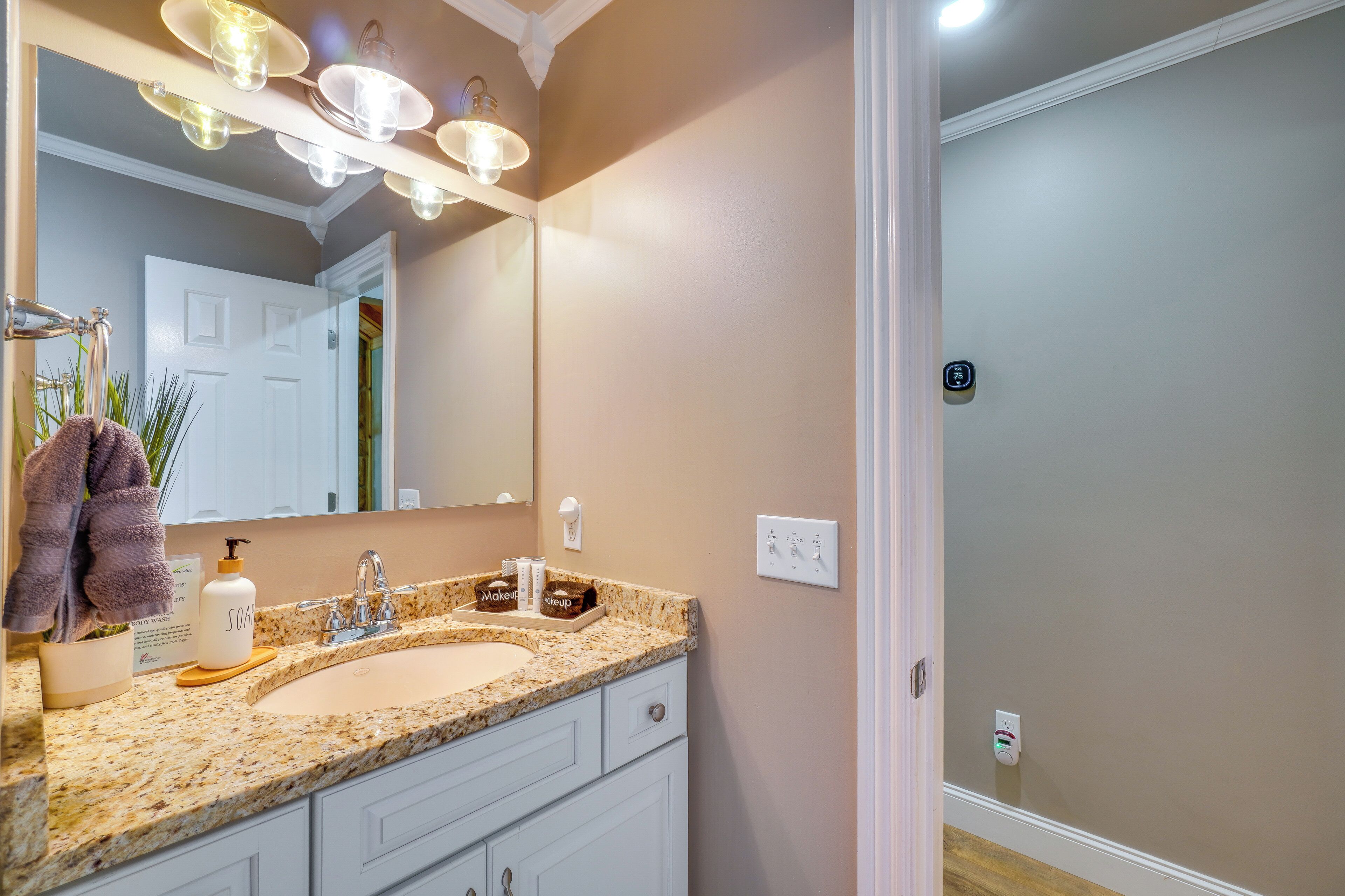 A bathroom with a double sink, a large mirror, and a light fixture above the mirror.