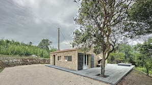 A small stone building with a gravel driveway, a wooden deck, and a tree in front. - Villa 2 Chambres Avec Jacuzzi (Bonifacio)