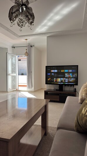 A living room with a TV, sofa, and a wooden coffee table. - Bright & sunny Terrace Flat (tanger)