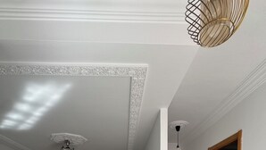 Un grand salon comprenant un canapé, une table basse et un téléviseur. Une porte donne accès à une autre pièce.