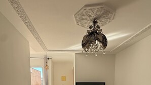 Un vaste espace de vie agrémenté d’une table basse en bois, d’un téléviseur posé sur un meuble et d’un luminaire décoratif au plafond.