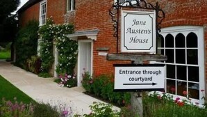 Senyal per a la casa de Jane Austen amb una fletxa que indica l'entrada a través del pati.