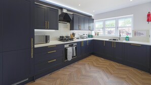 A modern kitchen with dark cabinets, stainless steel appliances, and a herringbone wood floor. - Huge House, Contractors/Families, 2X Free Parking (Hampshire)
