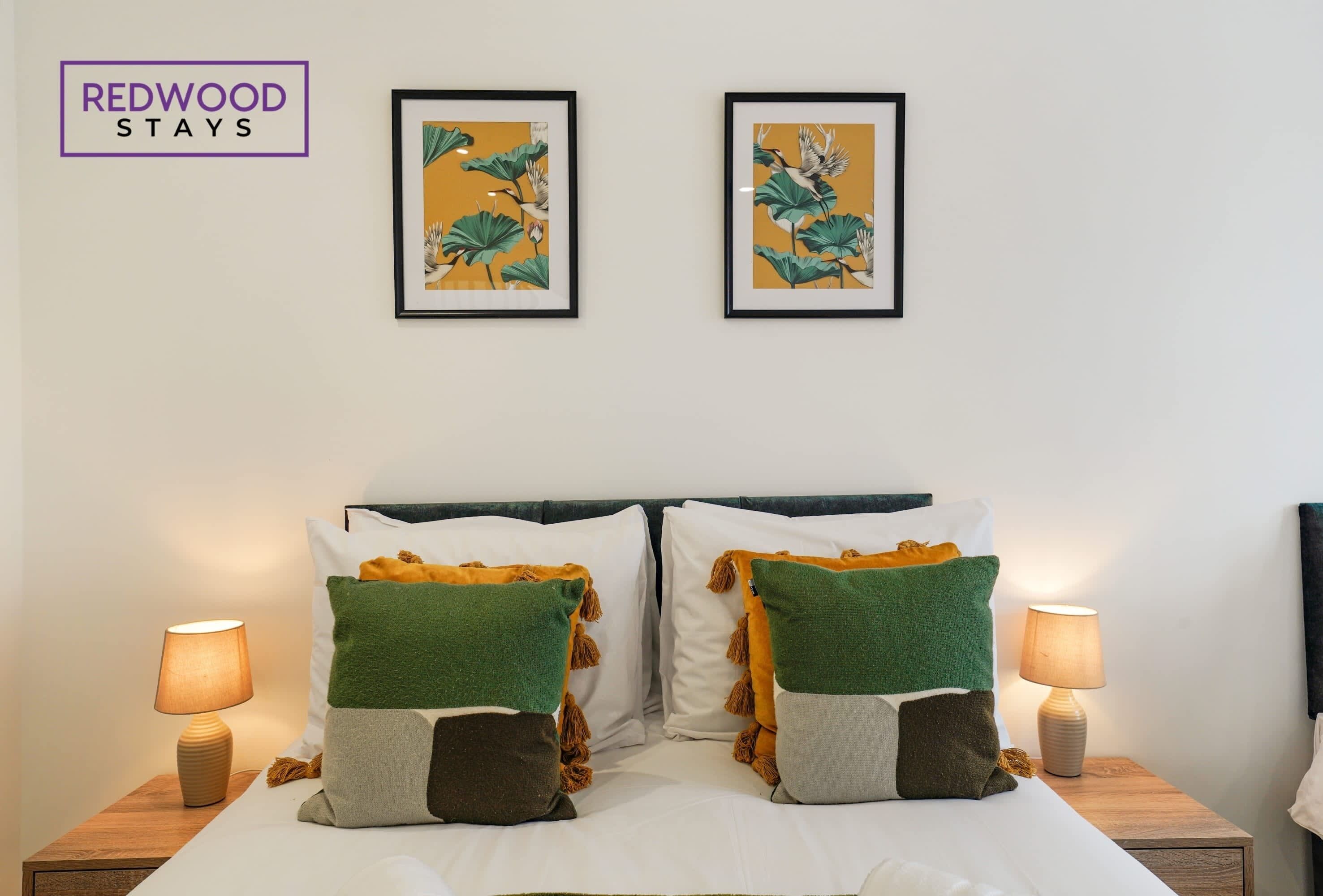 Une chambre d’hôtel avec un lit, deux œuvres d’art encadrées au mur et deux lampes de chevet.