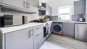 A modern kitchen with grey cabinets, a built-in microwave, a dishwasher, and a washing machine.