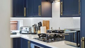 A modern kitchen with dark blue cabinets, a white countertop, and a gas stove. - Huge House, Contractors & Families, Free Parking (Hampshire)