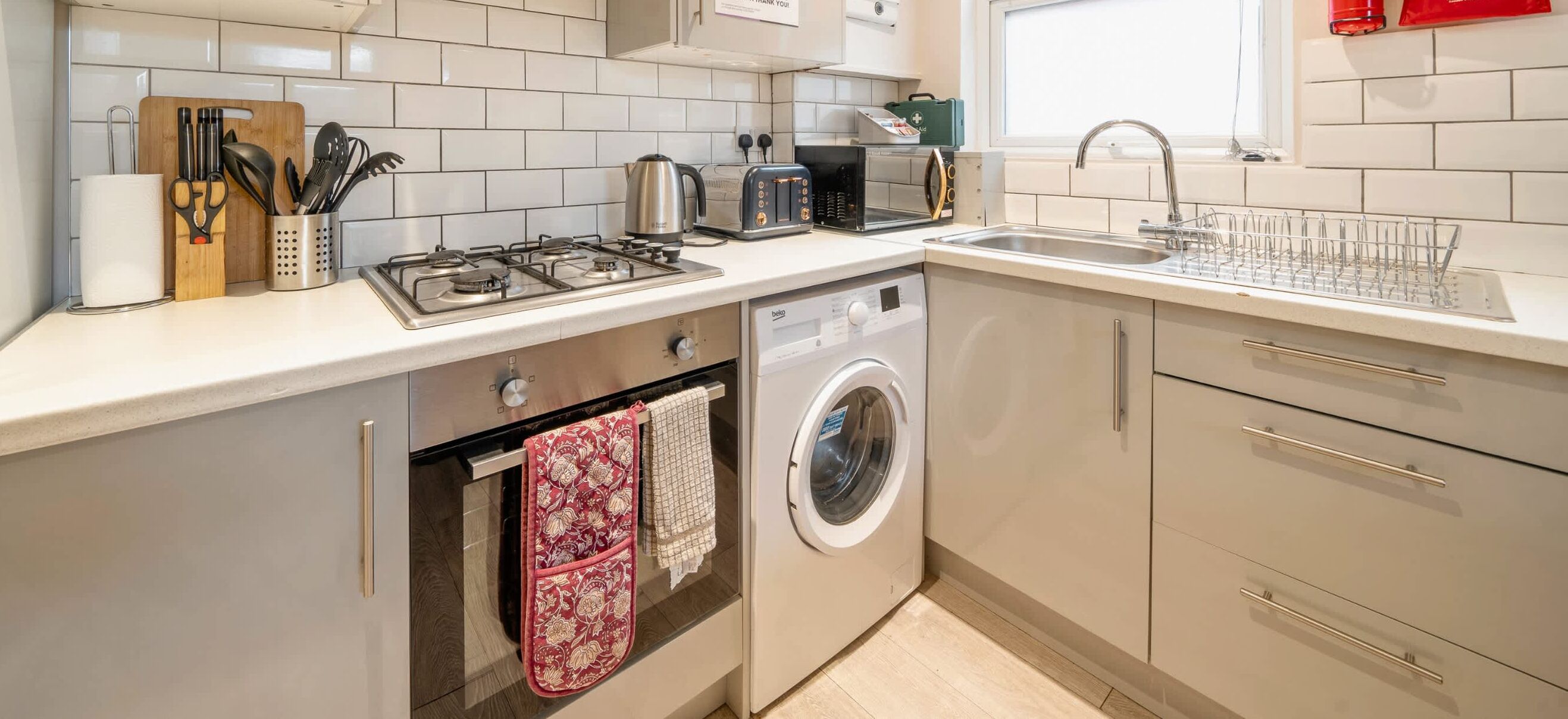 A modern kitchen with a gas stove, toaster, sink, and built-in washing machine.