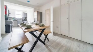 A modern kitchen with a wooden dining table, white cabinets, and a built-in oven. - Central Apartment | Contractors & Families | WiFi (Aldershot)