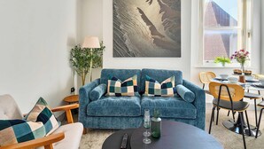 A living room with a blue sofa set, a coffee table, and a dining area with chairs and a table. - 1 Bed 1 Bath Apt, Contractors & Families, Parking (North Camp)