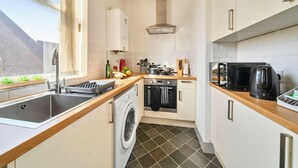 A compact kitchen with a washing machine, a microwave, and a kettle. - 1 Bed 1 Bath Apt, Contractors & Families, Parking (North Camp)