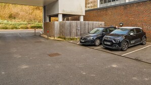 Un espace de stationnement où deux voitures sont garées à côté d’un bâtiment en briques.