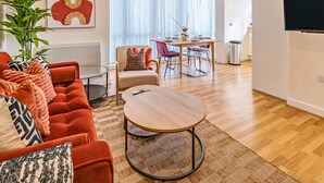 Un salon moderne avec un canapé rouge, une table basse ronde et un coin repas comprenant une table et des chaises.