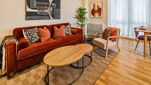 Un salon moderne avec un canapé rouge, une table basse en bois et un coin repas comprenant une table et des chaises en bois.