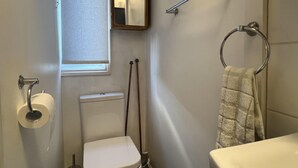 Une petite salle de bain comprenant des toilettes, un porte-serviettes, une barre d’appui et un miroir.
