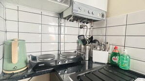Une cuisine équipée d’une cuisinière à gaz, d’une bouilloire et d’un porte-ustensiles.