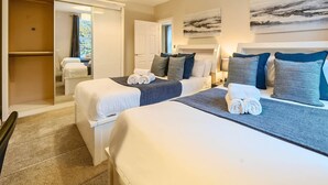 Une chambre d’hôtel avec deux lits, une armoire et une salle de bain.