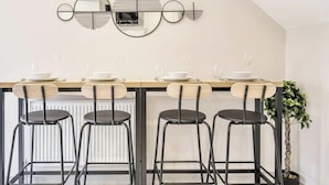 Un coin repas avec une longue table, quatre chaises et une plante sur le côté droit.