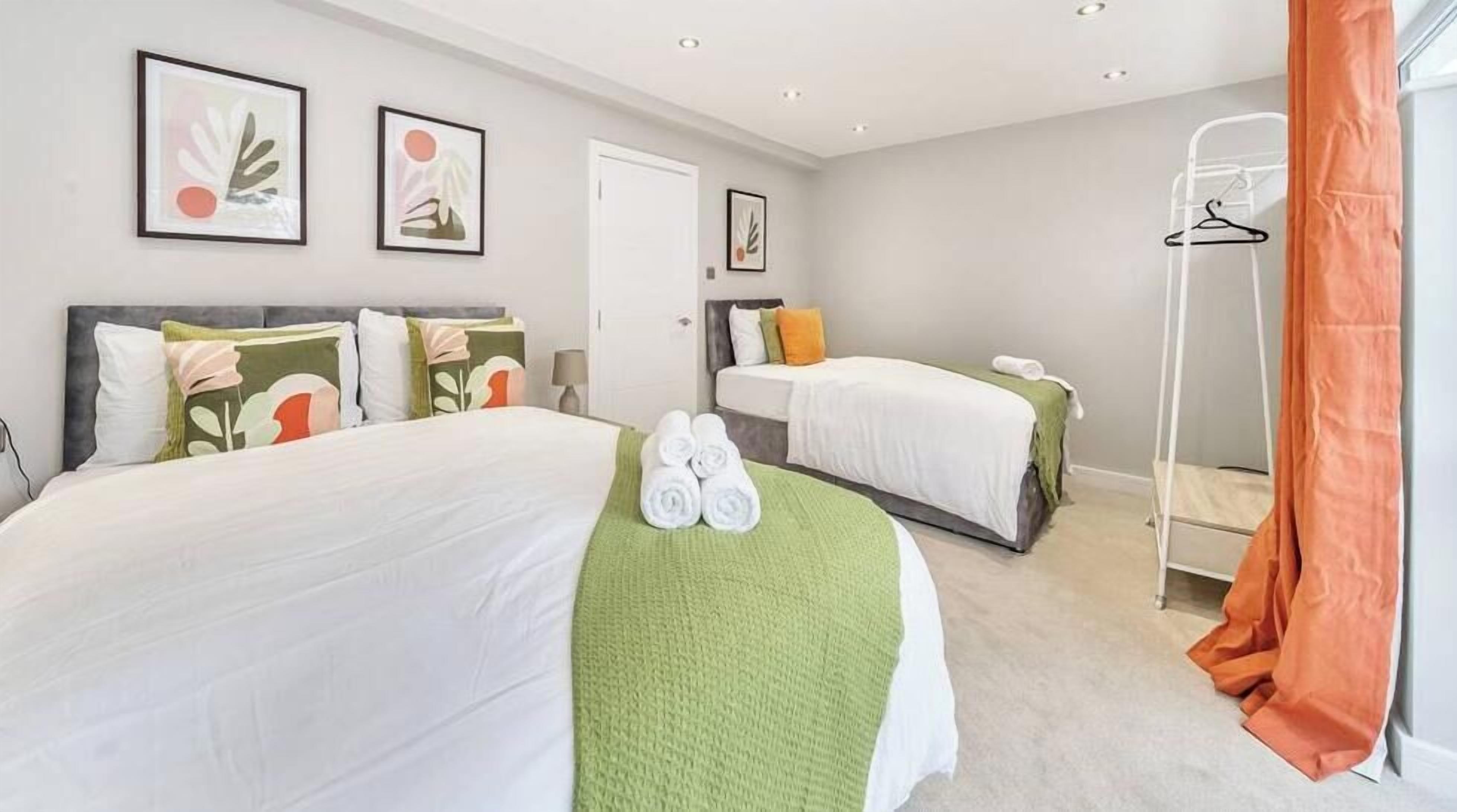 A hotel room with two beds, a wardrobe, and a bathroom.