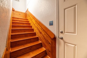 A wooden staircase with a white door at the bottom. - Southern Comfort - KDH MP 7.5, Semi-Oceanfront, 140 Yds to Beach, Hot Tub, Pets OK, Flex Stays (Kill Devil Hills)