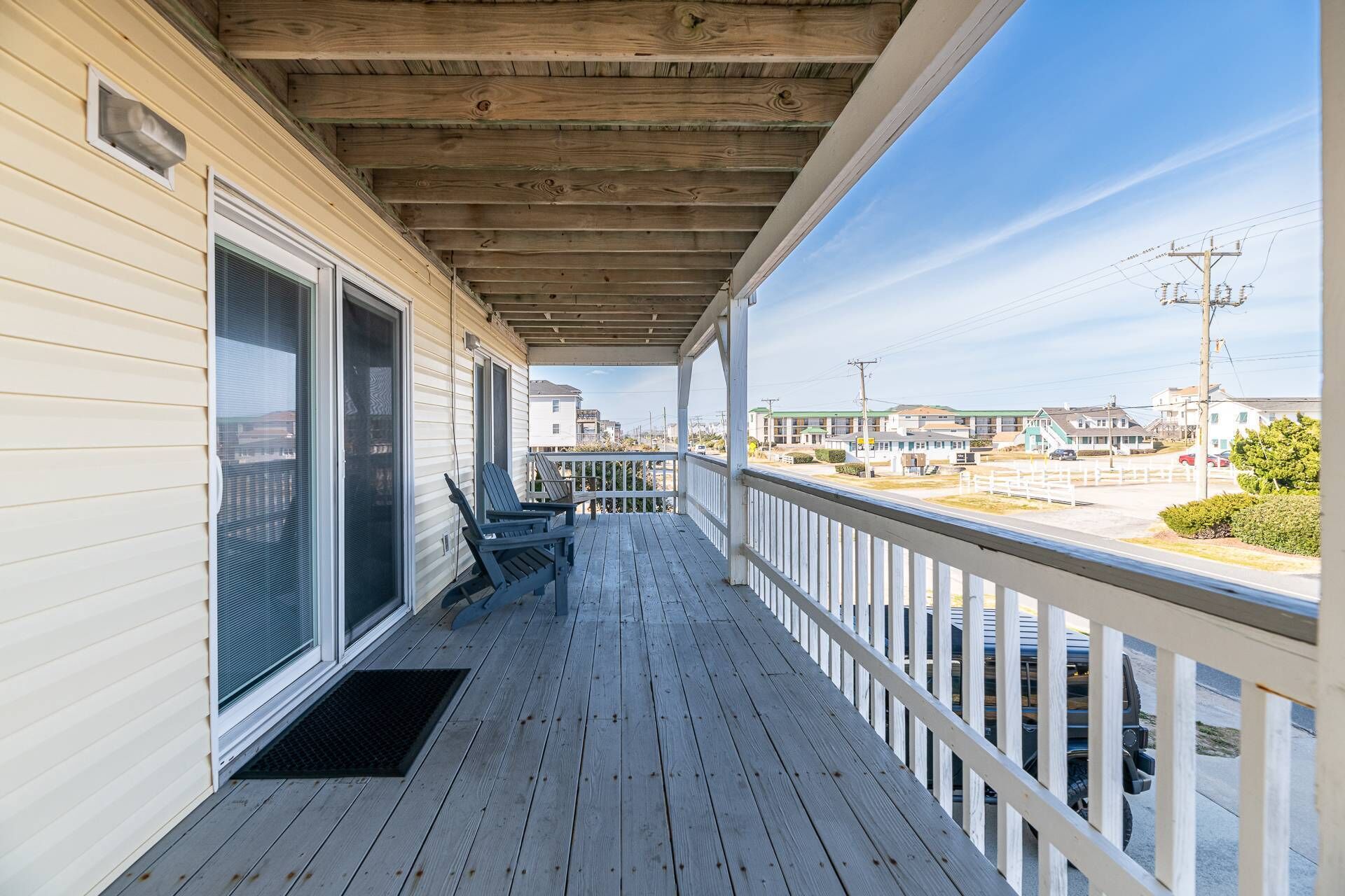 A wooden deck with a railing, a sliding glass door, and two chairs.