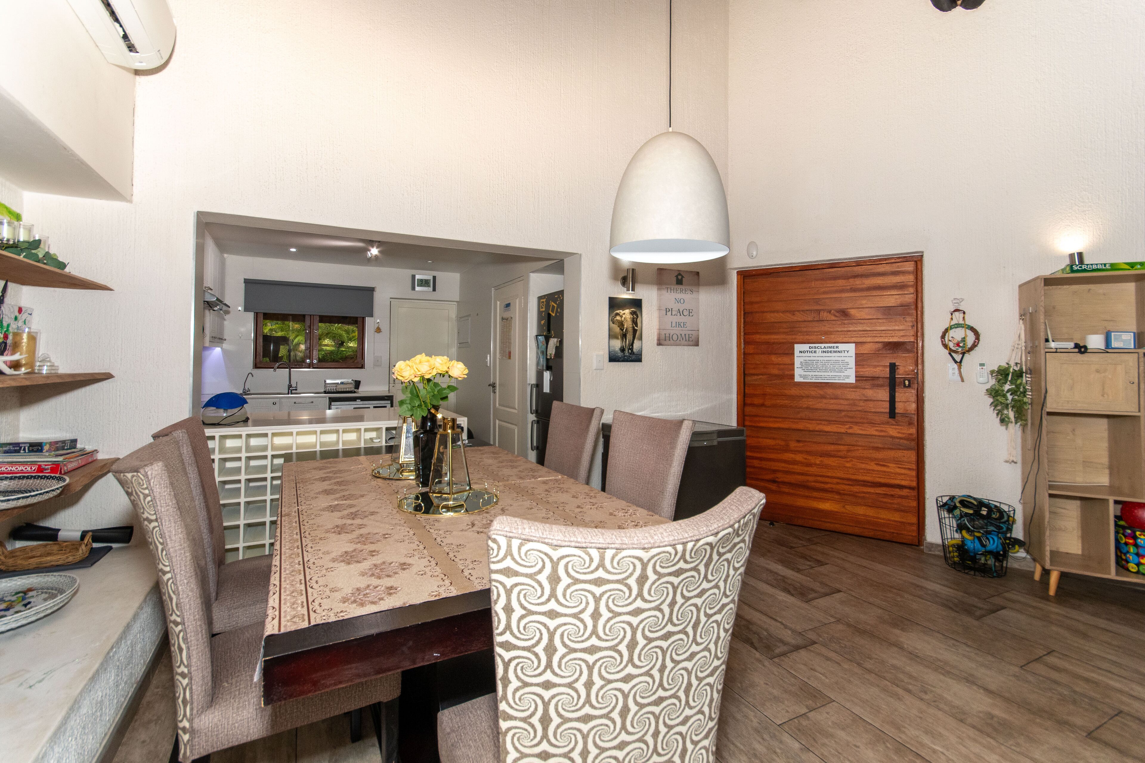 A dining area with a table set for four, a pendant light, and a wooden door.