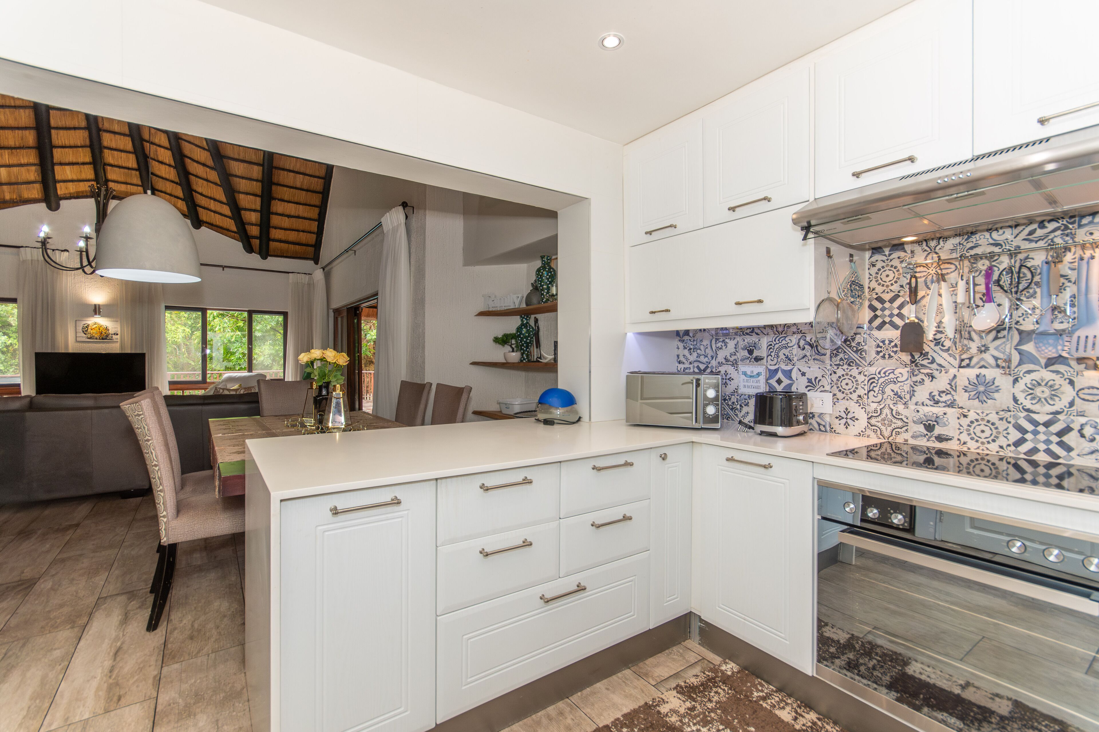 A modern kitchen with white cabinetry, a built-in oven, and a backsplash with blue and white tiles.