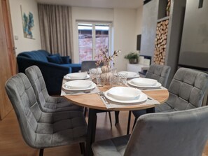 Enjoy a formal dining experience with a round table set for four, accompanied by comfortable chairs and elegant table settings.