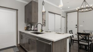 Una cocina moderna con electrodomésticos de acero inoxidable, una isla blanca e iluminación colgante.