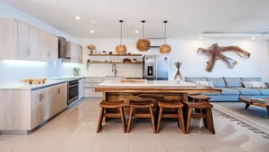 Une cuisine moderne dotée d’un îlot central, de meubles en bois et de luminaires suspendus.