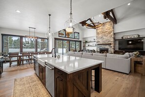 A spacious kitchen with a large island, wooden cabinets, and a stone accent wall. - Caldera Escape with Access to Exclusive Golf (Sunriver)