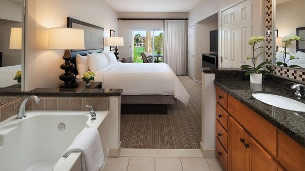 A hotel room with a large bed, a bathroom with a bathtub, a sink, and a view of the outdoors. - Spacious 1BR Villa at Marriott's Shadow Ridge – Full Kitchen + Golf Resort (Palm Desert)