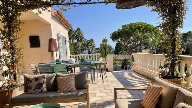 En udendørs terrasse med en sofa, stole og et spisebord.
