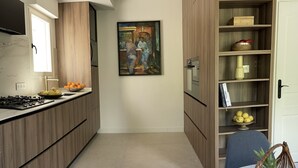 Et moderne køkken med træskabe, en marmor bordplade og et spiseområde med bord og stole.