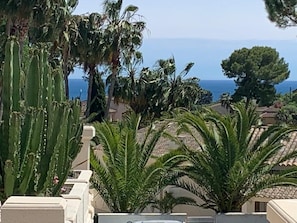 Stunning coastal views of the sea from a Mediterranean-style residence surrounded by lush vegetation.