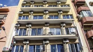 A multi-story building with balconies, air conditioning units, and a sign indicating a restaurant. - Pensión Pardo (Benidorm)
