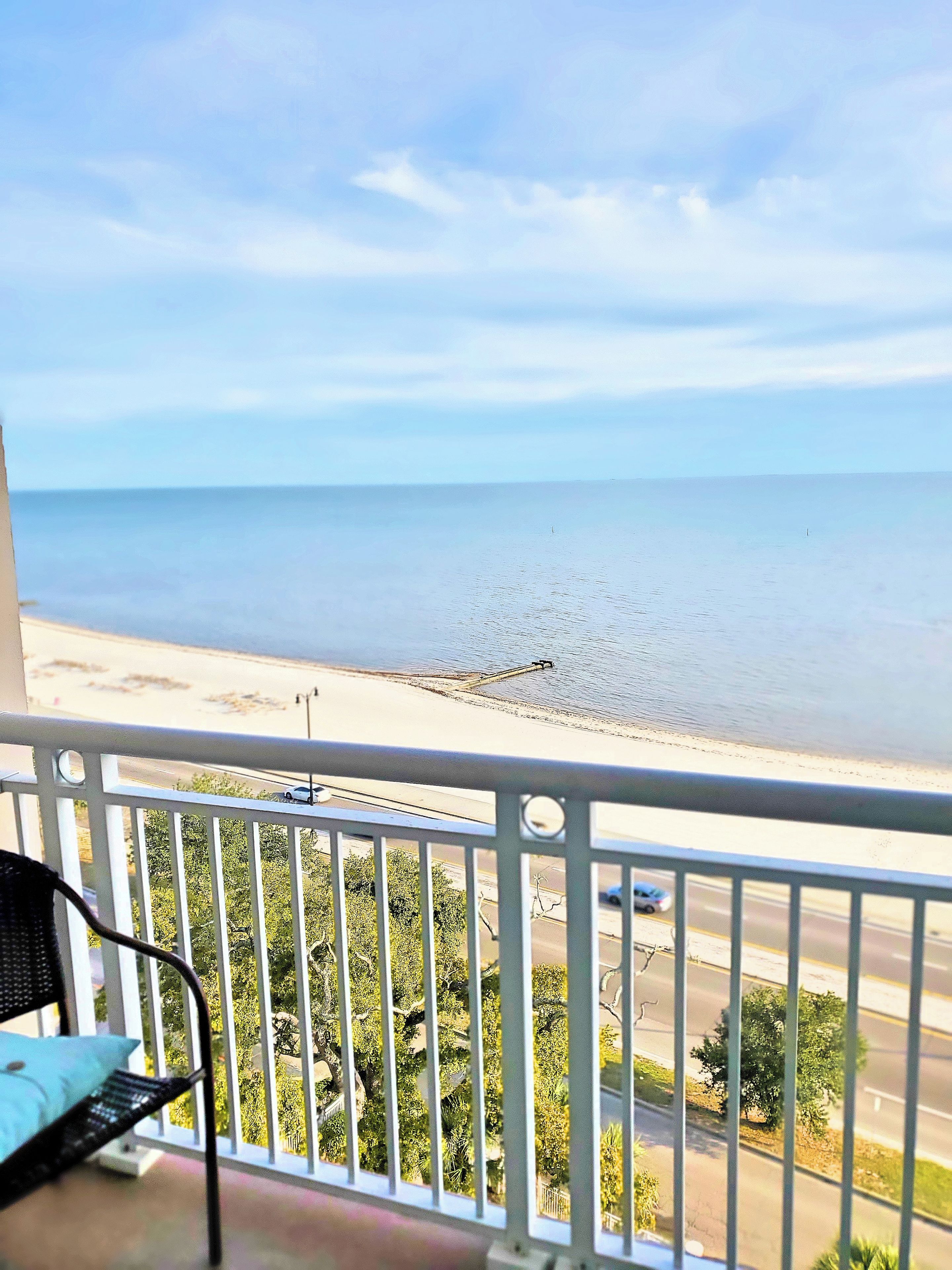 A balcony with a view of the sea and a road.