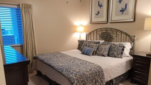 A bedroom with a bed, a nightstand, a dresser, and two framed pictures on the wall.