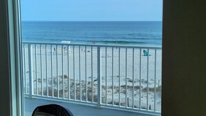 A view from a balcony overlooking a beach with a railing and a sandy shore.