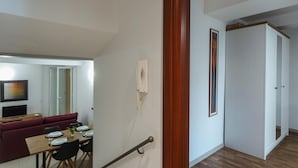 A modern living room with a dining area, a staircase, and a hallway leading to a bedroom. - Casana Downtown by Wonderful Italy (Genoa)