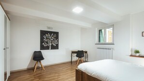A bedroom with a wooden floor, a bed, a desk, a chair, and a radiator. - Casana Downtown by Wonderful Italy (Genoa)