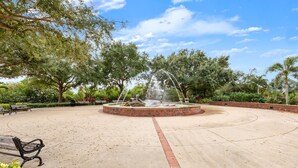 Ein Park mit einem kreisförmigen Brunnen, Bänken und Bäumen.